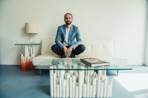 An executive in a formal suit sitting comfortably on a couch in a living room setting, with a confident expression and relaxed posture.